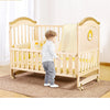 Child standing by the Multi-functional Wood Baby Crib Kids Cot with soft bedding in a bright room.