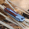 Wooden Handle Folding Tactical Pocket Knife resting on wood shavings, showcasing its classic design and modern utility.
