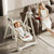 Adjustable Baby High Chair with Swing shown in use, a baby resting in a cozy position while a parent reads nearby.