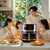 Family enjoying meals prepared with the 15-Liter Large-Capacity PBT Air Fryer on a sunny kitchen table.