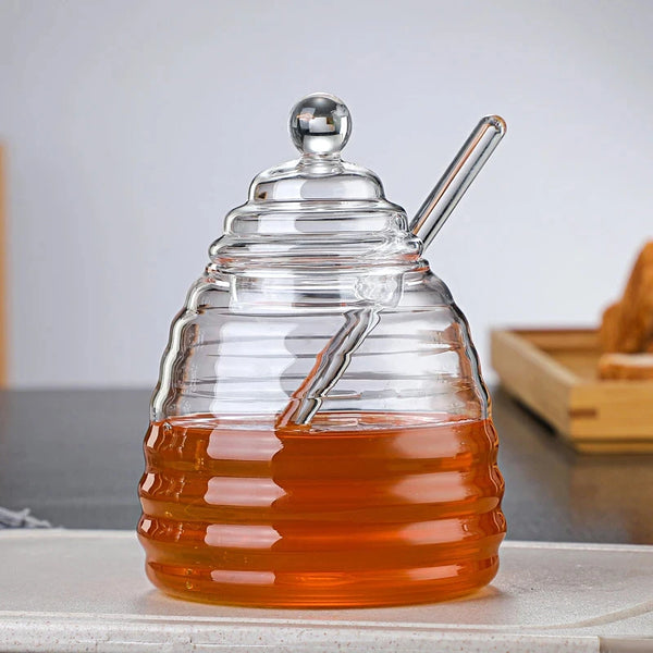 Hand-Blown Bee-Shaped Borosilicate Glass Honey Jar with honey and dipper, showcasing its unique design and functionality.