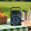 Portable Wireless BT Speaker with RGB Night Light on a picnic table with fruits and a flask in the background.