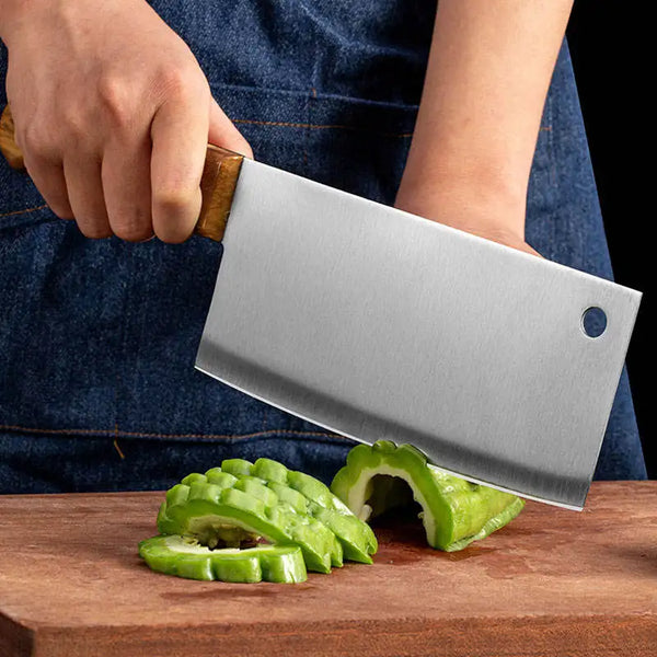 Heavy Duty Stainless Steel Bone Chopping Butcher Cleaver slicing through green vegetables on a wooden cutting board.