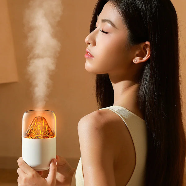 Woman using the Volcano USB Humidifier & Aroma Diffuser, enjoying soothing mist in a tranquil setting.