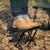 Person standing on a Collapsible Portable Camping Stool among autumn leaves, showcasing its compact design in an outdoor setting.