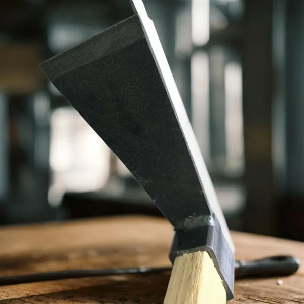 Carbon Steel Wooden Handle Garden Hoe next to a wooden surface, showcasing its durable design for garden maintenance.