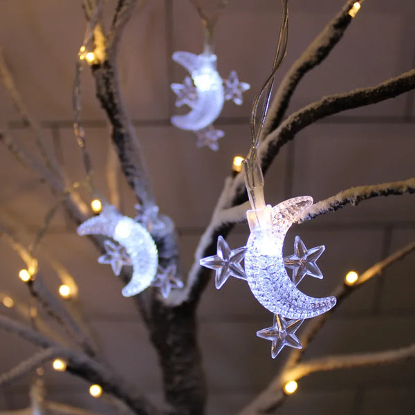LED moon and star Ramadan string hanging light illuminating a decorated tree branch.