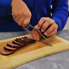 Person slicing sausage on a cutting board using the Aero Knife, highlighting its precision and sharpness.