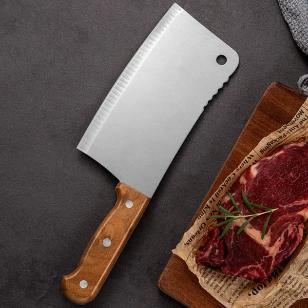 Heavy Duty Stainless Steel Bone Chopping Butcher Cleaver on a cutting board with raw meat and herbs.