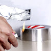 A hand using a lighter near heat resistant aluminum tape to demonstrate its fire resistance and durability.