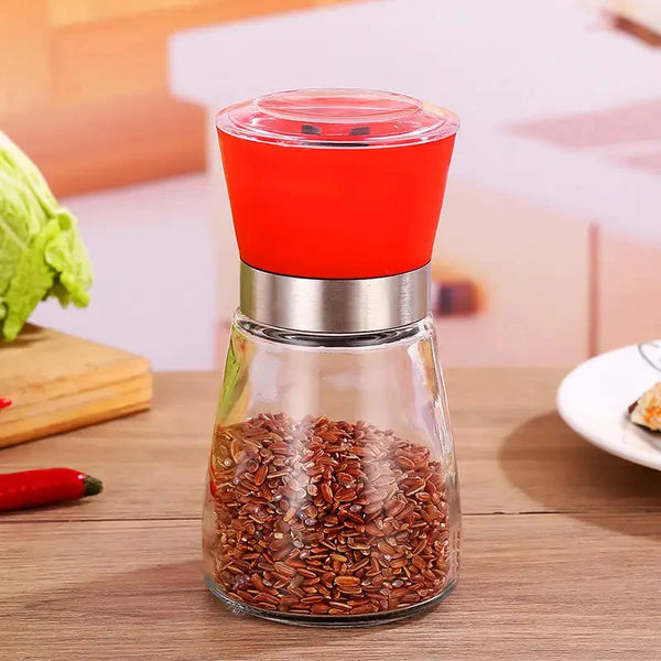 Manual Stainless Steel Pepper & Salt Grinder Mill with a red top and glass body, perfect for grinding spices.