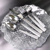 5-Piece Silverware Set displayed on a glass plate, featuring stainless steel flatware with textured handles.