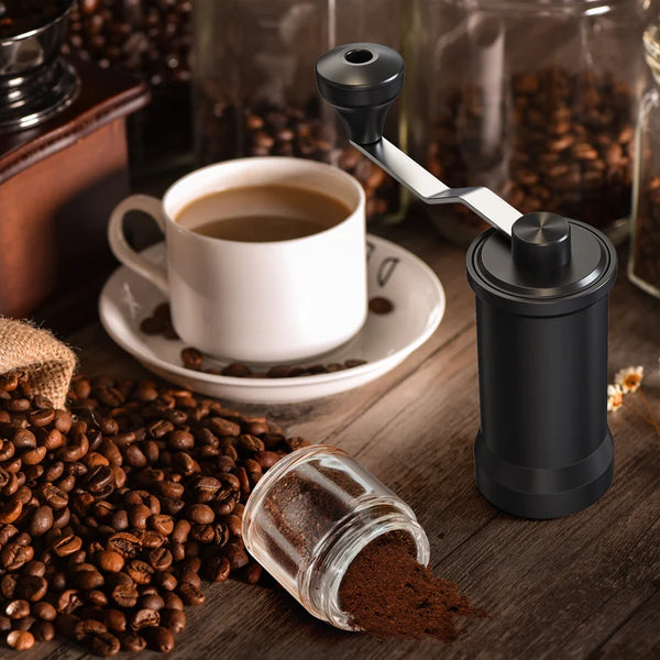 Manual Ceramic Coffee Grinder next to freshly brewed coffee cup and coffee beans.
