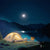 Outdoor IP65 Rechargeable Solar Light illuminating a campsite by a lake at night under a full moon.