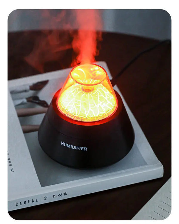 USB Mini Volcano Humidifier creating a soothing mist with a vibrant orange light, placed on a magazine.