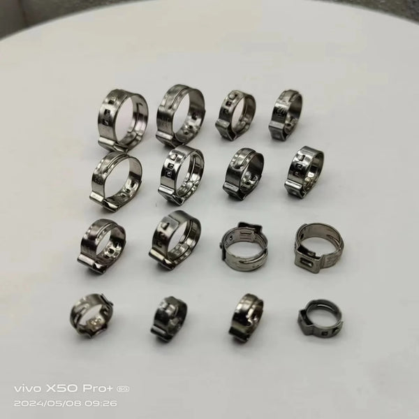 A collection of stainless steel double pipe clamps showcasing various sizes and designs for securing pipes and hoses.
