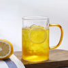 Heat Resistant Glass Beverage Cup filled with iced tea and lemon slices on a wooden table.