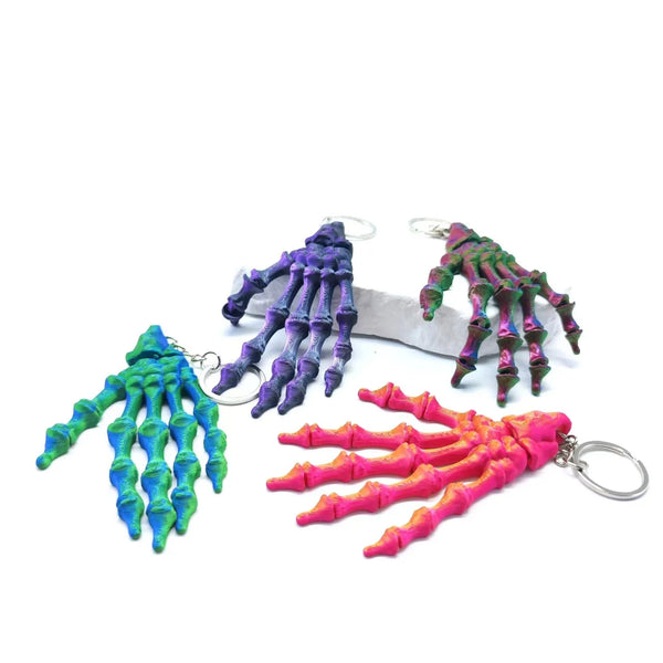 3D Printed Skull Hand Keychain Pendant showcasing colorful skeleton hand designs in purple, green, and pink.