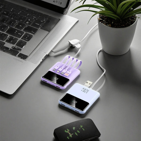 10000mAh Mini Power Bank with Built-In Cables charging multiple devices on a desk with a laptop and a plant.