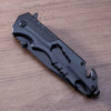 Iron Grip Full Metal Survival Folding Knife resting on a wooden surface, showcasing its sleek design and rugged features.