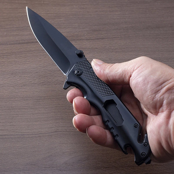 Hand holding the Iron Grip Full Metal Survival Folding Knife with a sleek black blade and textured grip.