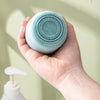 Reusable Silicone Ice Face Roller with Facial Brush in a person's hand, showcasing the textured pad for cleansing.