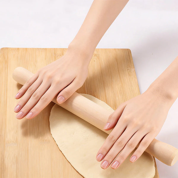Hands using a Wooden Rolling Pin to roll out dough on a bamboo cutting board.