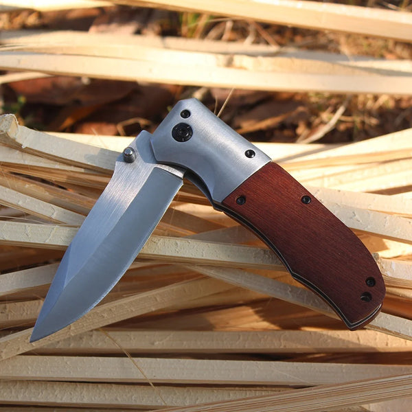 Wooden Handle Folding Tactical Pocket Knife lying on wooden shavings, showcasing its sleek blade and ergonomic design.