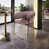 Upholstered Bar Stool with Curved Back and Black Metal Frame in a modern setting next to a stylish table.