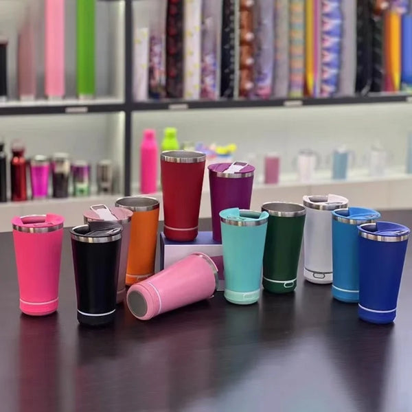 Collection of colorful 17oz Can Cooler Bluetooth Speaker Tumblers on a table with various designs and styles.