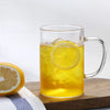 Heat Resistant Glass Beverage Cup filled with lemon iced tea and ice cubes on a wooden table.