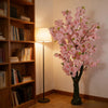 Artificial Silk Cherry Blossom Tree in a cozy interior with a bookshelf and lamp, adding elegance and color to the space.