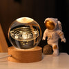 Crystal Milky Way LED Globe – 6 cm resting on wooden base with astronaut figurine beside it.