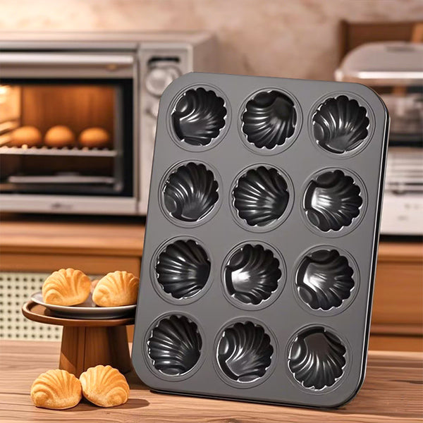 Carbon Steel Shell Shape Baking Mold displaying twelve shell-shaped cavities on a kitchen counter with baked treats.
