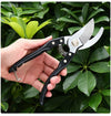 Steel Garden Bypass Pruner held in hand among vibrant green leaves for precise gardening cuts.