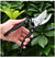 Steel Garden Bypass Pruner held in hand among vibrant green leaves for precise gardening cuts.