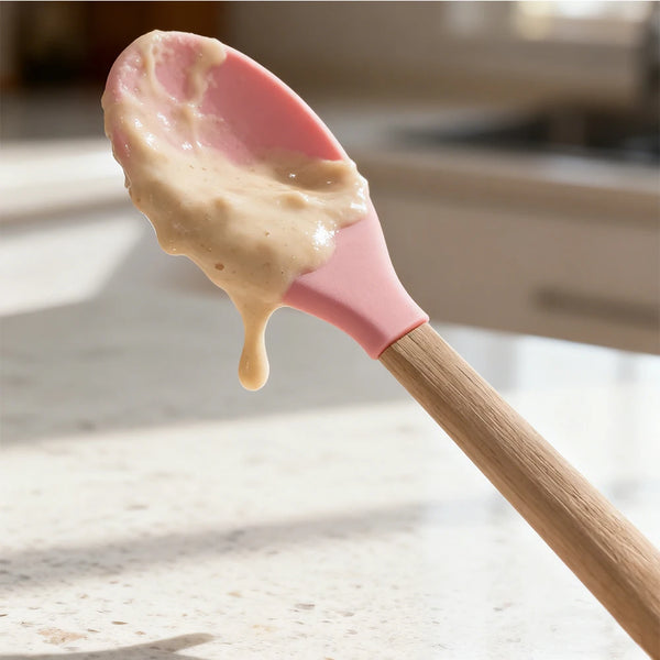 Silicone Cooking Spoon with Wooden Handle holding creamy mixture on a kitchen countertop.