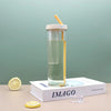 Reusable Clear Sports Water Bottle with Straw placed on a book with slices of lemon and ice cubes.