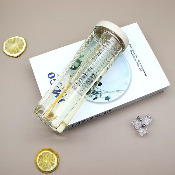 Reusable Clear Sports Water Bottle with Straw placed on a book with slices of lemon and ice cubes nearby.