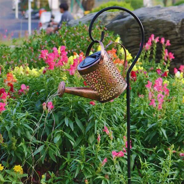 Solar-Powered Watering Can Garden Light elegantly illuminating a colorful garden with its enchanting glow.