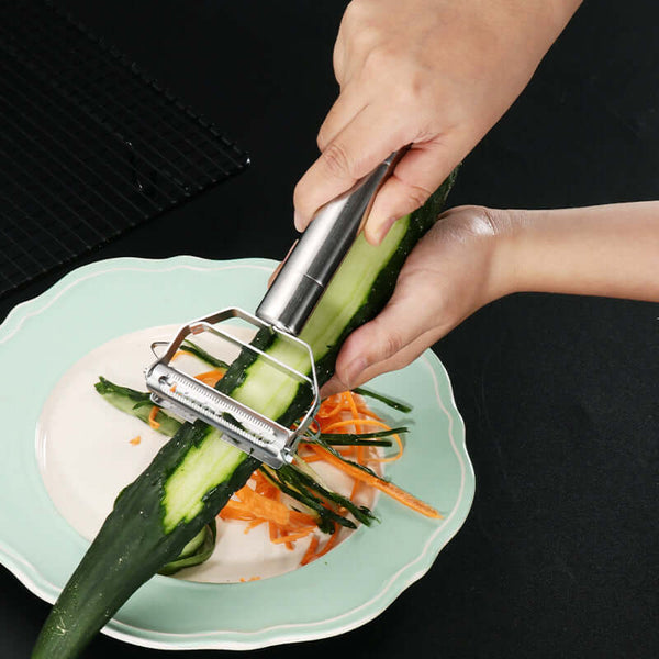 Person using a Stainless Steel Handheld Vegetable & Fruit Peeler on a cucumber placed on a green plate.