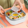 Stylish Two-Tier Airtight Lunch Box with compartments for salads, pasta, and sauces, held by hands on a vibrant background.