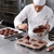 Chef using a Cartoon Character Non-Stick Baking Pan to pour chocolate batter in a professional kitchen.