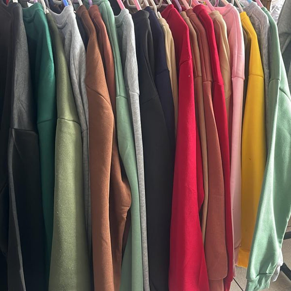 Colorful display of custom printing men tie dye sweatshirts hanging on a rack, showcasing various vibrant shades.
