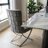 Grey Upholstered Dining Chair with Silver Frame placed beside a marble dining table in a modern interior.