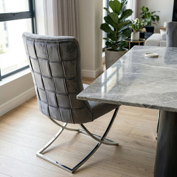 Grey Upholstered Dining Chair with Silver Frame placed beside a marble dining table in a modern interior.