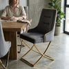 Modern Elegant Upholstered Dining Chair with sleek design next to a wooden table and a woman enjoying coffee.