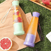 Smoothie Blender Cups in green and purple on a picnic blanket with fresh fruits for healthy blending on the go.