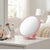 Round Portable Makeup Mirror in soft pink color, placed on a vanity table surrounded by beauty products.