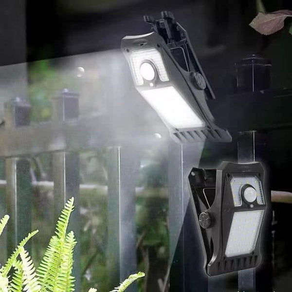 Solar Glow Clip Light clipped onto a fence illuminating a garden area with bright light.